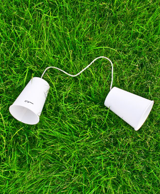 Bild zeigt ein einfaches Dosentelefon im Gras liegend